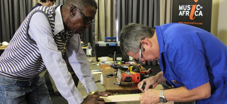 Christian Carver shows one of the project participants how to make a guitar.